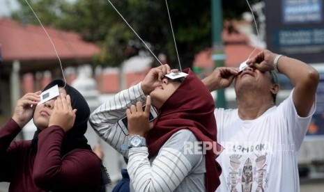 Melihat Gerhana Matahari Yogyakarta. Warga dan wisatawan mencoba megamati proses gerhana matahari dengan alat bantu di Halaman Masjid Gede, Yogyakarta, Kamis (26/12).