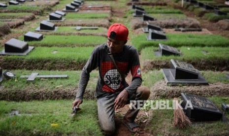 Penjaga makam beraktifitas di Tempat Pemakaman Umum (TPU) Pondok Ranggon, Cipayung, Jakarta, Minggu (30/12).