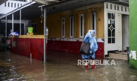 Seorang warga meninggalkan rumahnya saat terjadi banjir di kawasan Jatipadang, Pasar Minggu, Jakarta, Rabu (1/1).