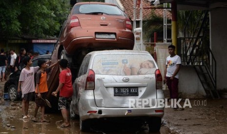 Anak-anak melihat mobil yang rusak pascabanjir di Perumahan Pondok Gede Permai Bekasi, Jawa Barat, Kamis (2/1).