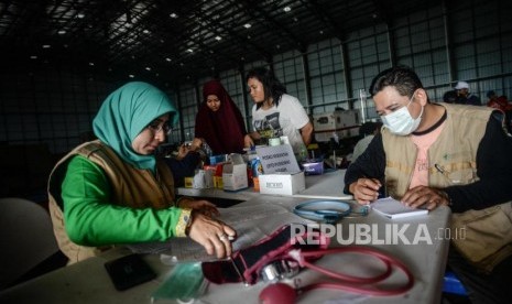 Belum ada data mengenai jumlah sekolah yang terdampak banjir. Foto: Petugas Puskesmas Jati Asih mengecek data korban banjir di posko Gudang Badan Nasional Penanggulangan Bencana, Jalan Pondok Gede Permai, Jati Asih, Kota Bekasi, Jawa Barat, Jumat (3/1).