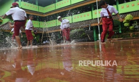 Pelayanan Kesehatan Pengungsi Ditingkatkan Pascabanjir. Foto: Siswa Sekolah Dasar Negeri Kapuk Muara 01 bermain air saat kerja bakti bersama pasca banjir di Jakarta, Senin (6/1/2019).