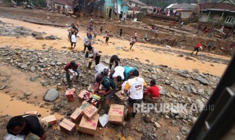 Sejumlah warga mengambil bantuan logistik yang dijaruhkan melalui helikopter di Kampung Muhara, Lebak Gedong, Lebak, Banten, Senin (6/1/2020).