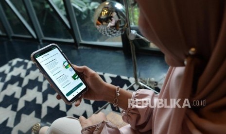 Seorang anak muda menggunakan aplikasi Mandiri Syariah mobile di telepon genggamnya di salah satu kafe di Jakarta, Rabu (8/1).