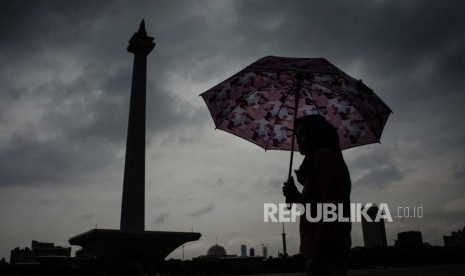 Sejumlah warga melindungi badannya dari air hujan dikawasan Monas, Jakarta (ilustrasi)