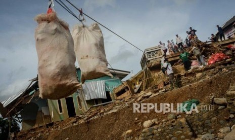 Warga menerima bantuan menggunakan bantuan keretan baja di Kampung Muara, Desa Banjarsari, Kecamatan Lebak Gedong, Banten, Senin (13/1).