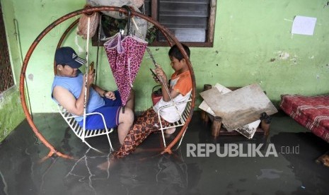 Dua orang anak bermain gawai di rumahnya yang terendam banjir  (ilustrasi)