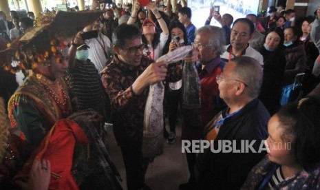 Gubernur Sumatera Barat Irwan Prayitno (kedua kiri) mengalungkan kain kepada salah satu wisatawan asal China saat penyambutan di Bandara Internasional Minangkabau (BIM), Padangpariaman, Sumatra Barat, Ahad (26/1/2020).