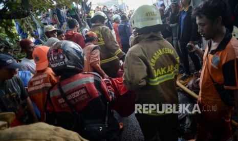 Petugas Pemadam Kebakaran membawa kantong jenazah saat evakuasi korban kebakaran di pemukiman padat penduduk kawasan Peninggaran Timur, Kebayoran Lama, Jakarta, Senin (27/1).