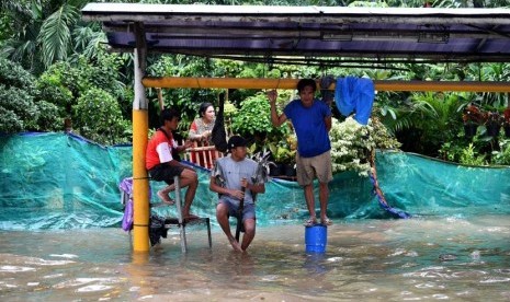 Warga menunggu surutnya banjir di Jalan Letjen Suprapto, Jakarta Pusat. BPBD DKI menggunakan SMS blast untuk menginformasikan peringatan dini banjir. Ilustrasi.