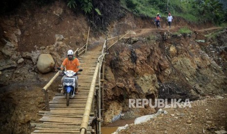 Pengendara motor melintasi jembatan darurat di Desa Cileuksa, Kecamatan Sukajaya, Kabupaten Bogor, Jawa Barat, Kamis (13/2).