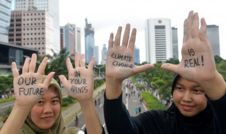 Dua orang perempuan yang tergabung dalam aksi jeda untuk iklim menunjukkan aspirasi pada tangannya saat aksi di JPO kawasan Jalan Sudirman, Jakarta, Minggu (23/2/2020).