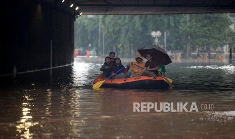 Warga melintasi banjir dengan menggunakan perahu karet dikawasan terowongan Jalan DI Panjaitan, Cawang, Jakarta.