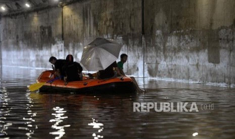 Warga melintasi banjir dengan menggunakan perahu karet dikawasan terowongan Jalan DI Panjaitan, Cawang, Jakarta, Selasa (25/2).