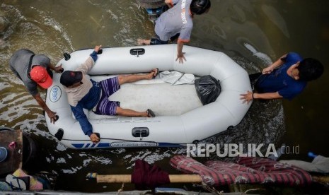 Sejumlah warga mengevakuasi seorang warga di area yang terendam banjir di Jalan Satria IV, Kelurahan Jelambar, Jakarta Barat, Selasa (25/2).