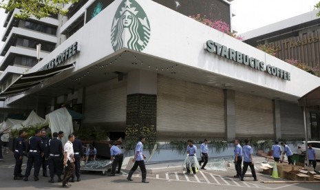  Pekerja membersihkan pecahan kaca di lokasi serangan teror, depan gerai Starbucks, Jalan Thamrin, Jakarta, Jumat (15/1). 