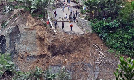 Sejumlah warga menyaksikan jalan raya yang amblas di lokasi bencana longsor di Desa Clapar, Madukara, Banjarnegara, Jateng, Rabu (30/3).  (Antara/Anis Efizudin)