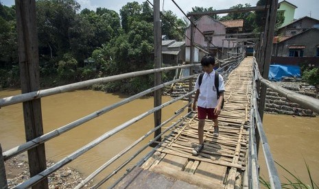 Seorang pelajar menyeberang melalui jembatan gantung di atas Sungai Ciliwung menuju kawasan Kampung Poncol di Jakarta, Senin (4/4). (Antara/Widodo S. Jusuf)