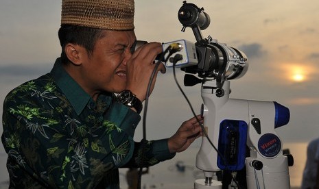 Seorang pria mencoba membidik bulan melalui teodolit sederhana hasil ciptaannya saat mengamati bulan untuk menentukan mulainya puasa di Pantai Jerman, Kuta Selatan, Bali, Ahad (5/6). (Antara/Nyoman Budhiana)