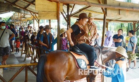 Pengunjung antre menaiki kuda, di De Ranch, Jalan Maribaya, Lembang, Kabupaten Bandung Barat, Jumat (8/7). (Republika/Edi Yusuf)