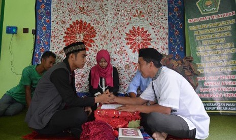 Petugas memandu akad nikah sepasang mempelai di Kantor Urusan Agama (KUA) Kecamatan Palu Selatan, Palu, Sulawesi Tengah, Kamis (22/12). 