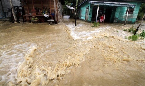 Warga berdiri di teras rumahnya yang terendam banjir. ilustrasi