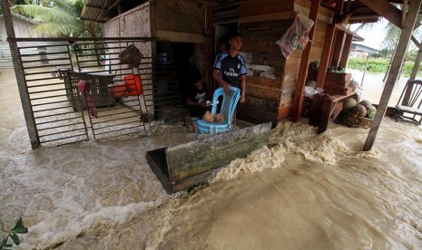 Warga berdiri di teras rumahnya yang terendam banjir di Desa Nga, Lhoksukon, Aceh Utara, Aceh, Rabu (4/1). 