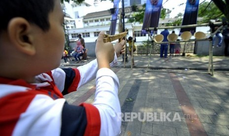  Seorang anak bermain pistol kayu dengan peluru karet saat gelar kaulinan budak di Jalan Soekarno, Kota Bandung. 