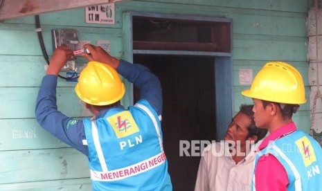   Petugas PLN memasang meteran listrik di sebuah rumah warga di Desa Sabang Mawang Balai, Kecamatan Pulau Tiga, Natuna, Kepri.