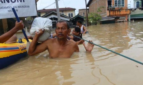 Sejumlah warga melintasi banjir yang merendam pemukiman penduduk di pinggiran Sungai Deli, Kecamatan Medan Maimun, Medan, Sumatera Utara, Selasa (7/11).