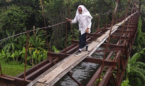 Siswa menyeberangi jembatan gantung yang difungsikan sebagai saluran air, di Ngemplak, Boyolali, Jawa Tengah, Senin (13/11).