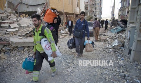  Warga mengevakuasi barang-barang milik mereka dari reruntuhan bangunan yang hancur akibat gempa di kota Sarpol-e-Zahab di Provinsi Kermanshah, Iran, Senin (13/11).