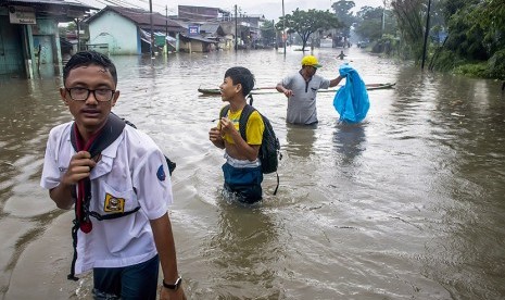 Warga melintasi banjir di kawasan Baleendah, Kabupaten Bandung, Jawa Barat, Senin (13/11). 