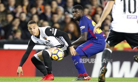  Pemain Barcelona Samuel Umtiti berebut bola dengan pemain Valencia Rodrigo pada laga La Liga Spanyol di stadion Mestalla, Valencia, Senin (27/11) dini hari WIB.