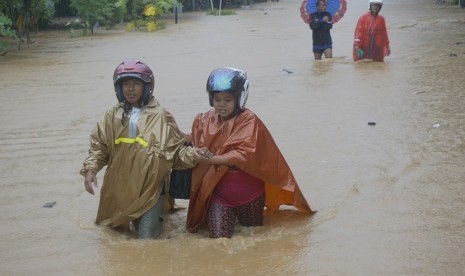 Warga menyeberangi banjir bandang yang memutus jalur lintas selatan Desa Hadiwarno, Pacitan, Jawa Timur, Selasa (28/11). 