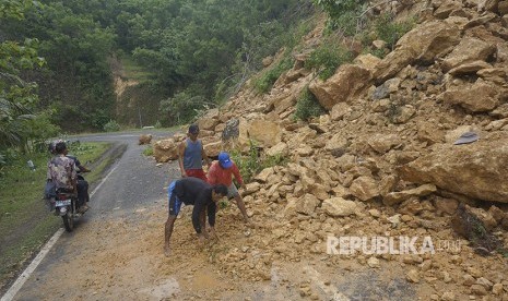 Warga menyingkirkan material longsor di jalur lintas selatan ((JLS) Pacitan, Jawa Timur, Rabu (29/11). 