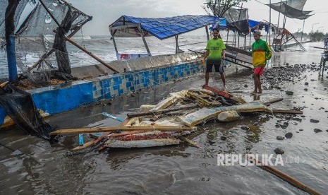 Sejumlah warga melintas di tenda warung yang roboh akibat ombak laut di Pantaisari, Pekalongan, Jawa Tengah, Jumat (1/12).