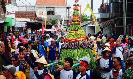 Warga memikul gunungan berisi hasil bumi saat karnaval Maulid Nabi, di Kudus, Jawa Tengah, Ahad (3/12).