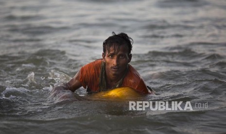 Seorang pria Rohingya berusaha melewati sungai Naf di perbatasan Myanmar-Bangladesh, untuk melarikan diri dari genosida militer Myanmar terhadap muslim Rohingya.