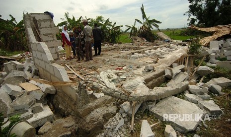 Sejumlah warga berada di dekat rumah yang hancur karena puting beliung di Desa Bojongnangka, Pemalang, Senin (1/1). 