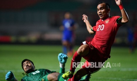 Pemain Timnas Indonesia U-23 Riko Simanjuntak (kanan) berjibaku dengan penjaga gawang Timnas Thailand U-23 Nont Muangngam dalam pertandingan uji coba di Stadion Pakansari, Cibinong, Bogor, Jawa Barat, Ahad (3/6) malam.