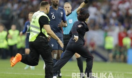 Petugas keamanan mengejar seorang wanita yang berlari masuk ke lapangan di Stadion Luzhniki, Moskow, Ahad (15/7) malam WIB. 