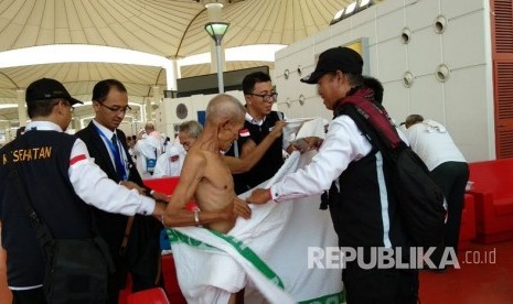  Hikmah Memakai Pakaian Ihram. Foto:  Petugas membantu jamaah haji Indonesia mengenakan pakaian ihram di Bandara King Abdul Aziz, Jeddah, Senin (30/7).