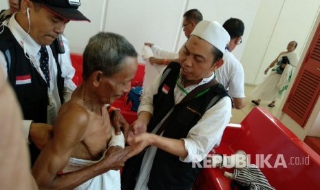 Petugas membantu jamaah haji Indonesia mengenakan pakaian ihram di Bandara King Abdul Aziz, Jeddah, Senin (30/7).