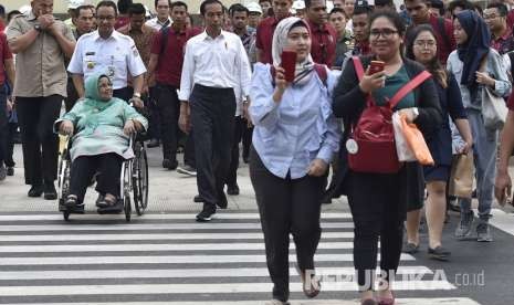 Presiden Joko Widodo (tengah) bersama Gubernur DKI Jakarta Anies Baswedan (ketiga kiri) dan ibu dari Gubernur DKI Jakarta Aliyah Rasyid Baswedan (kedua kiri) menyeberangi Pedestrian Light Control (Pelican Crossing) di Jalan MH Thamrin, Jakarta, Kamis (2/8).