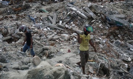 Rahmat (27) dan adiknya tengah mencari besi bekas di area yang terdampak likuefaksi Perumnas Balaroa, Palu, Sulawesi Tengah, Senin (15/10).