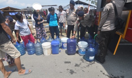 Pengungsi korban gempa dan pencairan tanah (likuifaksi) mengambil air bersih dan air siap minum pada kendaraan Water Treatmen milik Polri dilokasi pengungsian di Petobo, Palu, Sulawesi Tengah, Selasa (16/10/2018). 