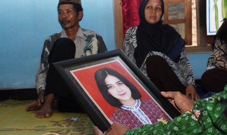 Seorang kerabat memegangi foto salah seorang pramugari pesawat Lion Air JT 610 yang mengalami kecelakaan, Alfiani Hidayatul Solikah di depan kedua orangtua Alfiani, Slamet (kiri) dan Kartini (kedua kiri) di rumahnya Desa Mojorejo, Kebonsari, Kabupaten Madiun, Jawa Timur, Selasa (30/10/2018).