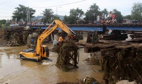 Alat berat membersihkan material banjir berupa kayu dan sampah yang tersangkut di jembatan rel kereta api pasca banjir, di kelurahan Alai Parak Kopi, Padang, Sumatera Barat, Sabtu (3/11/2018). 