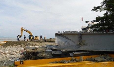 Petugas menggunakan alat berat  untuk meratakan sisa reruntuhan puing Jembatan Palu IV atau Jembatan Ponulele, Palu, Sulawesi Tengah paska gempa dan tsunami, Kamis (8/11).